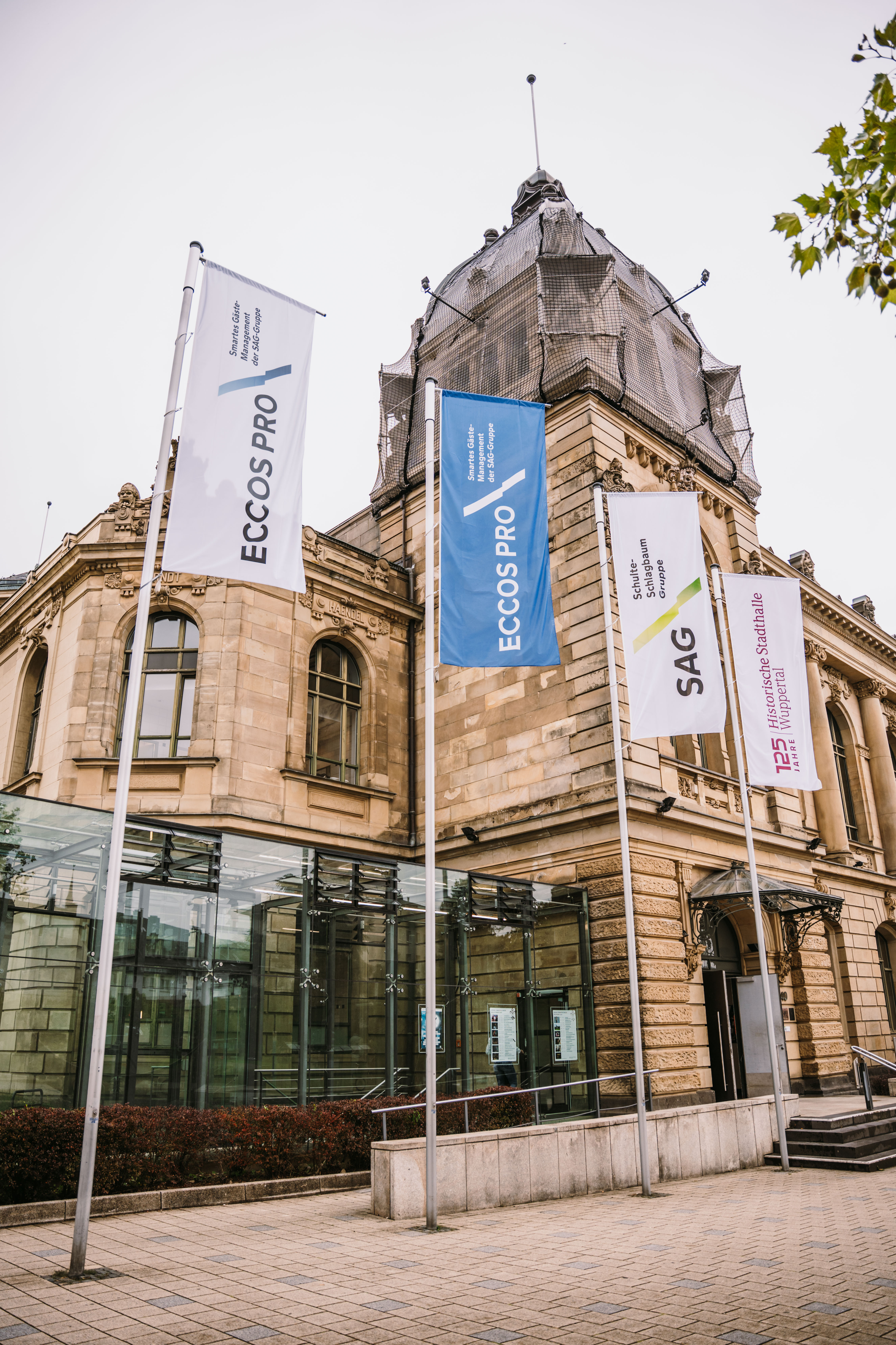 Foto von der Wuppertaler Stadthalle, im Vordergrund 4 Flaggen mit den Logos der Eccos Pro und der Schulte Schlagbaum AG 