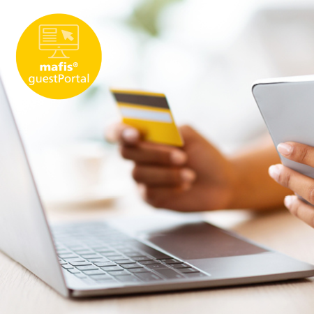 Person hält Kreditkarte und Smartphone für eine digitale Online-Zahlung am Laptop.