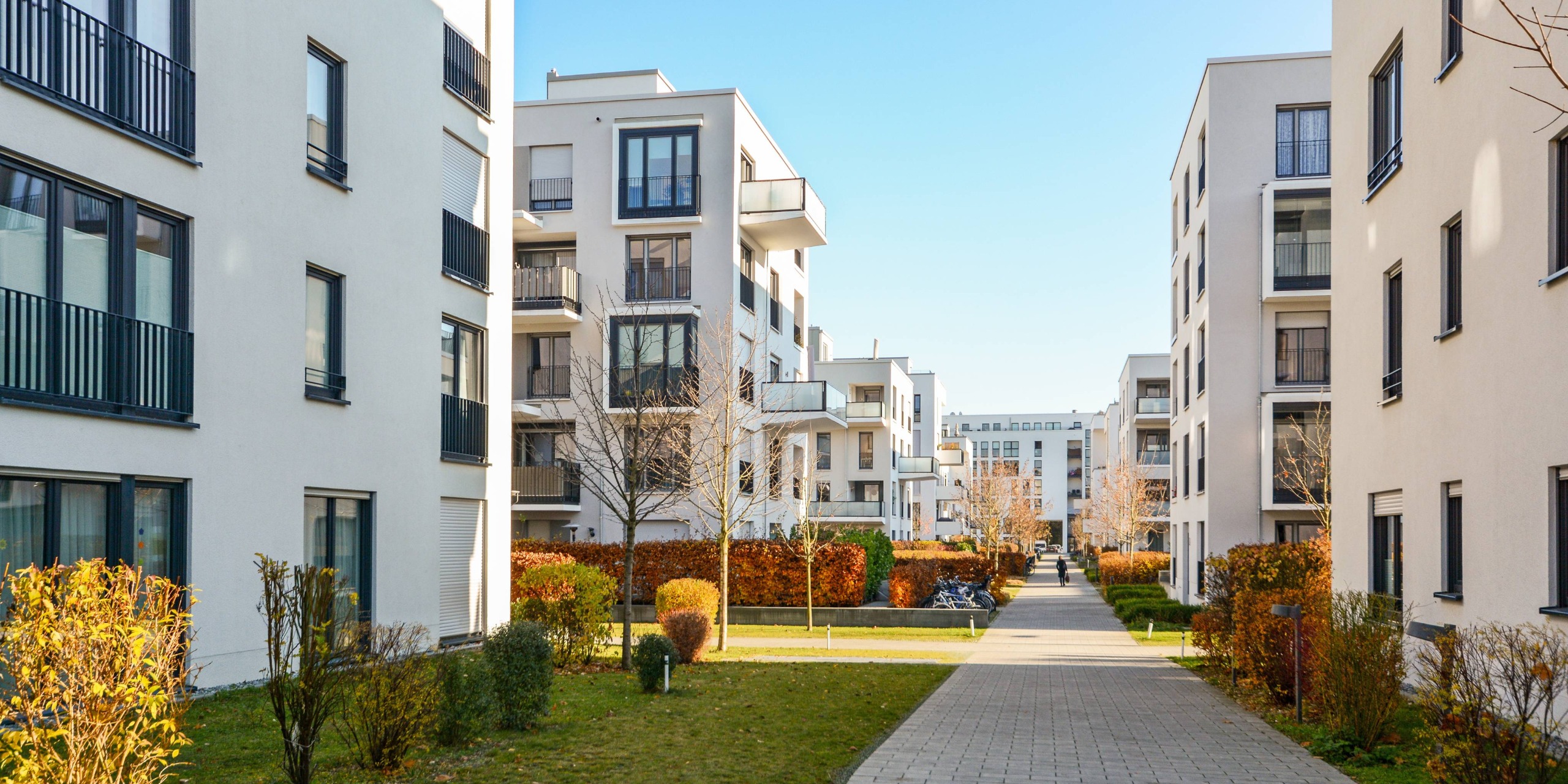 Wohnsiedlung mit modernen Mehrfamilienhäusern und in der Mitte ein Spazierweg